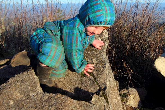 Toddler climbing rocks on the hiking trail